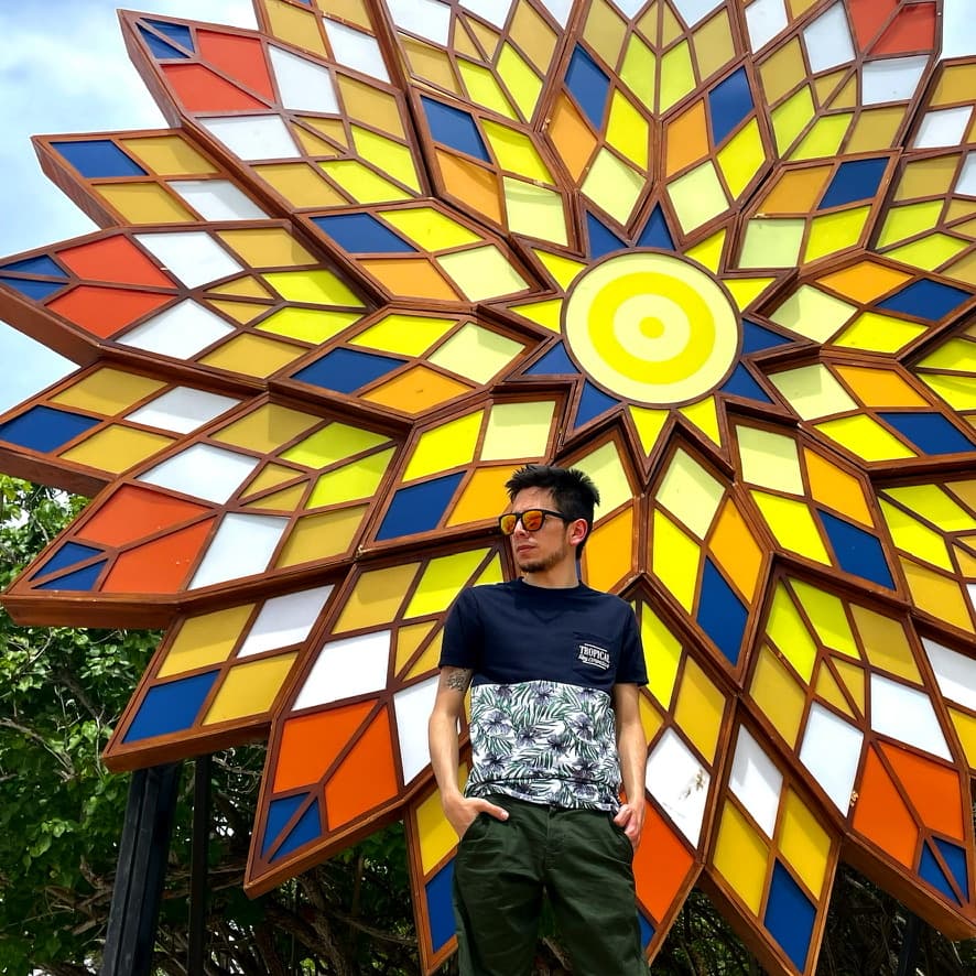 A visitor beside a sunburst art installation on the island